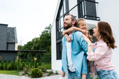Eine Familie steht freudestrahlend vor einem Haus